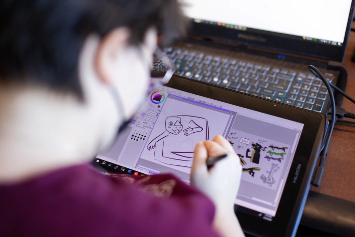 View over the should of a student drawing on a tablet with a stylus.