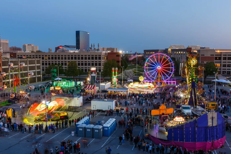 Jagapalooza carnival rides and games fill a parking lot on the IUI campus at dusk as students line up for their turn to ride.
