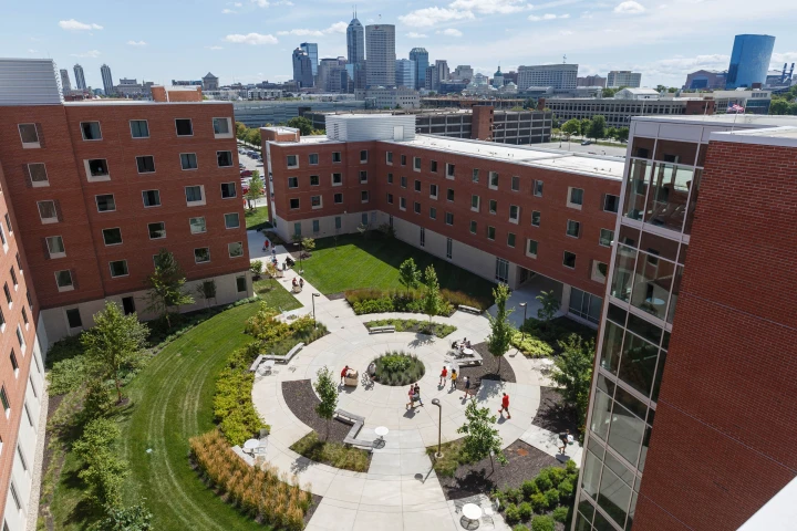 View from high level looking down on the landscaped courtyard of North Hall as new students and family members move items into rooms for the start of a new school year.