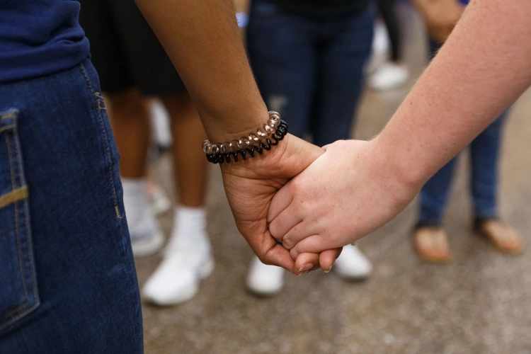 A pair of hands hold each other seen from behind.